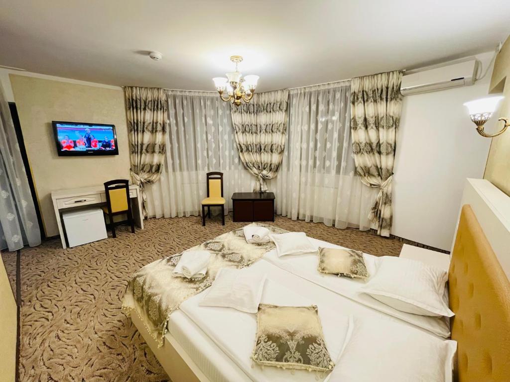 a bedroom with a large white bed and a tv at Pensiunea Ianis Piatra Neamt in Piatra Neamţ