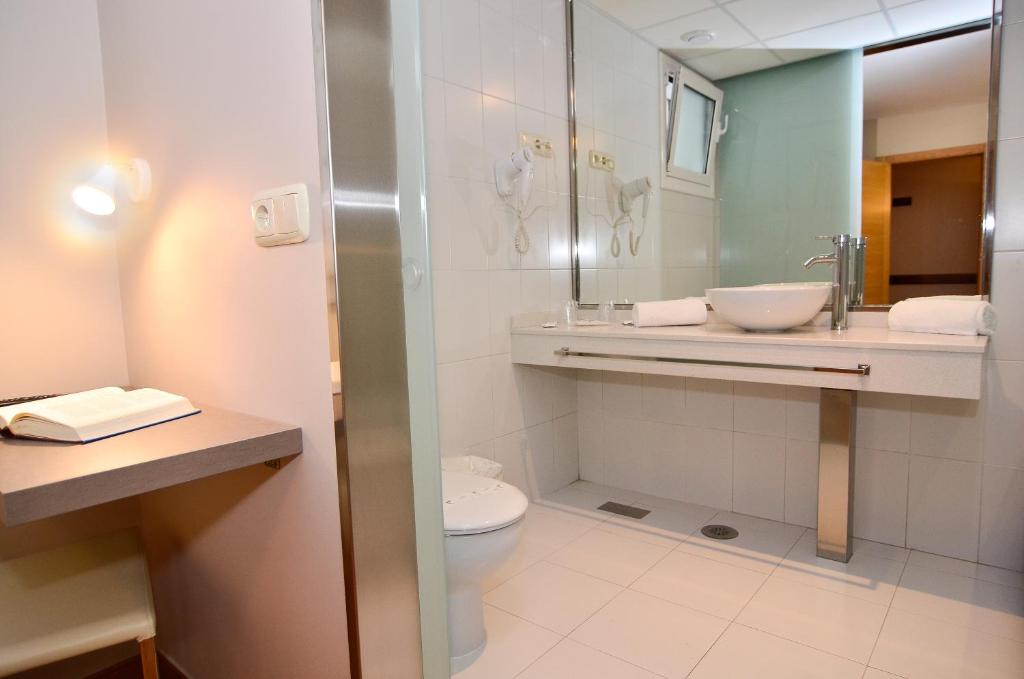 a bathroom with a toilet and a sink and a mirror at Hotel Jucamar in Cangas de Morrazo