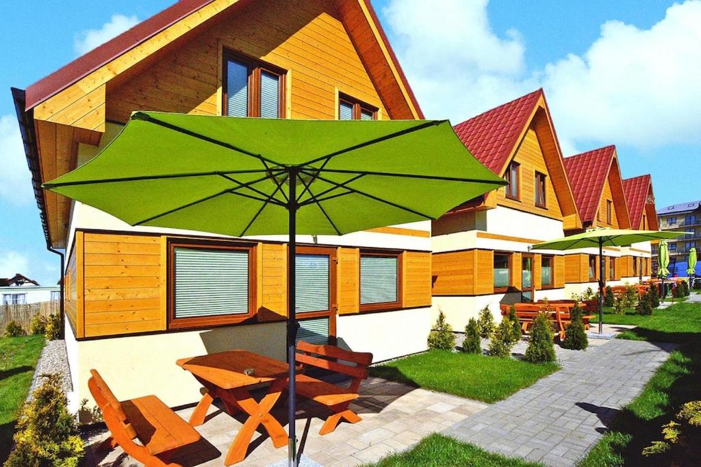 einem grünen Regenschirm vor einem Gebäude in der Unterkunft Holiday resort, Sarbinowo in Sarbinowo