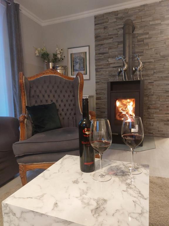 twee glazen wijn op een tafel voor de open haard bij Grenzberg Appartements in Bad Gastein