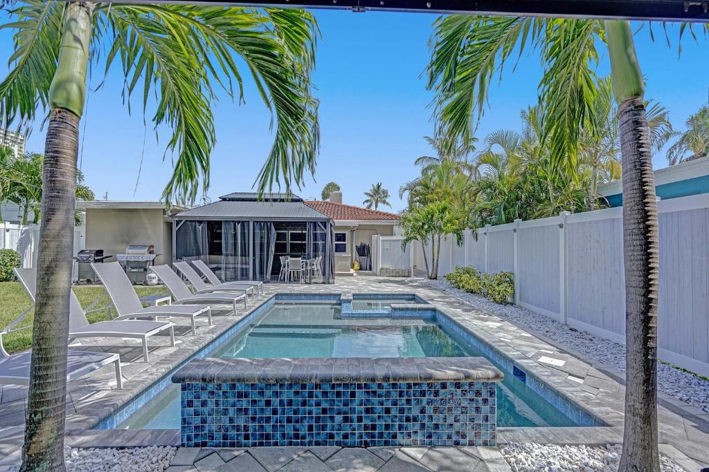 a swimming pool with palm trees in a yard at Ocean Breeze Villa in Pompano Beach