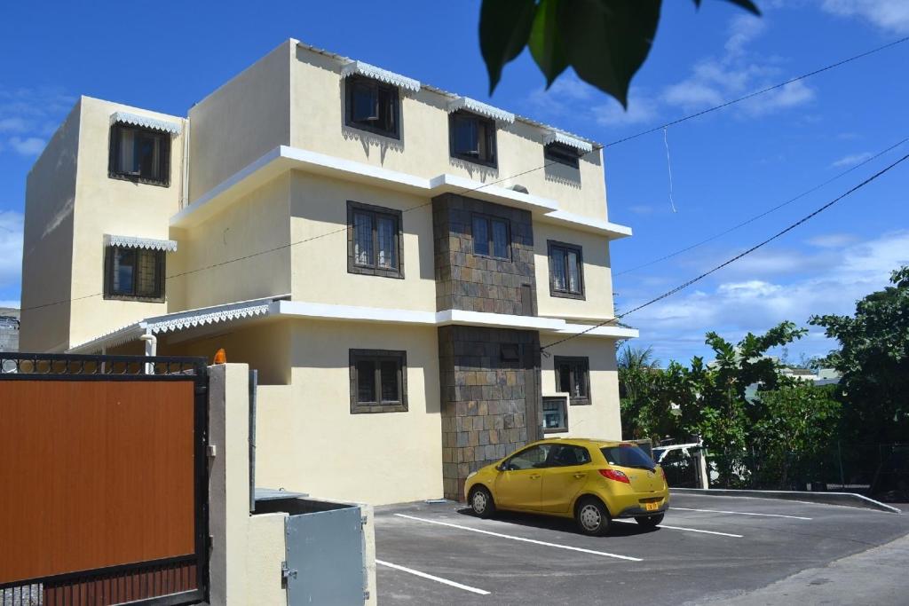 un coche amarillo estacionado frente a un edificio en Apartment is calm locality, en Flic en Flac