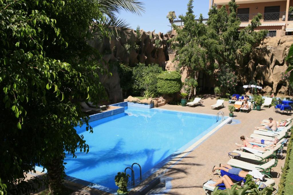 Imperial Holiday Hôtel & spa في مراكش: مسبح مع كراسي جلوس وناس في منتجع
