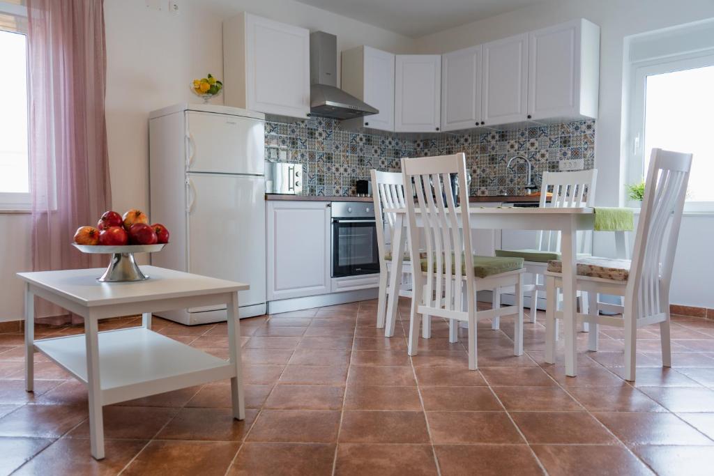 een keuken met witte kasten en een tafel en stoelen bij Apartment Ivanka in Vrsi
