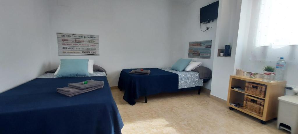 a bedroom with two beds with blue sheets and a table at La Mongeta Màgica. in Castellón de la Plana