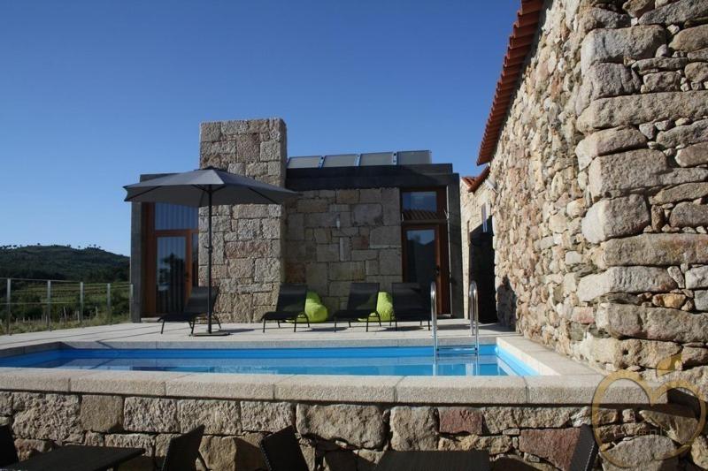 a swimming pool with an umbrella next to a stone building at Mallus Agroturismo in Misquel
