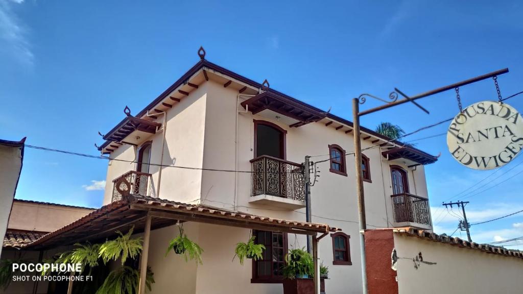 Casa blanca con balcones y una señal en Pousada Santa Edwiges, en Tiradentes