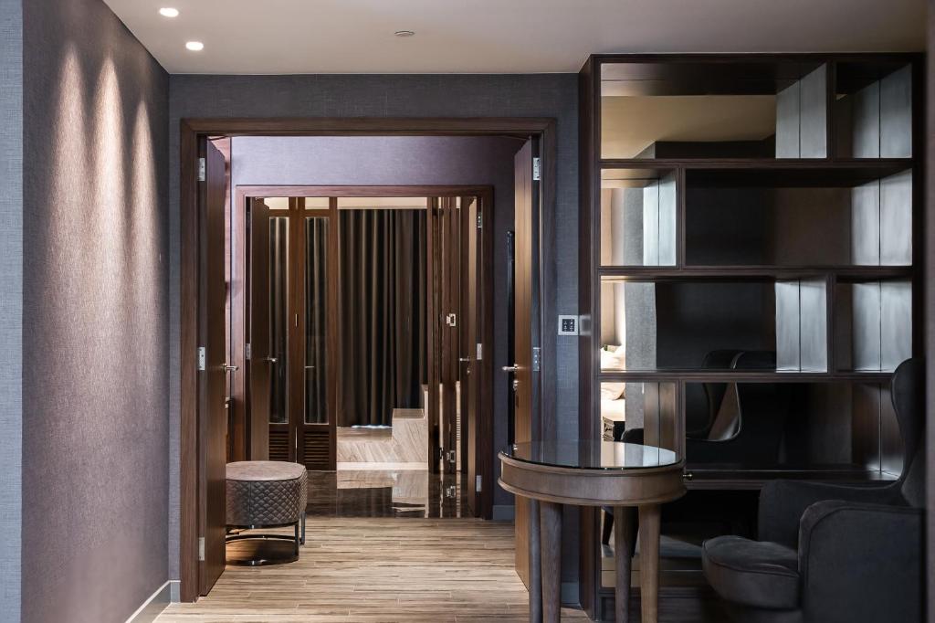 A compact desk and chair sit beside open shelving in a suite entrance area.