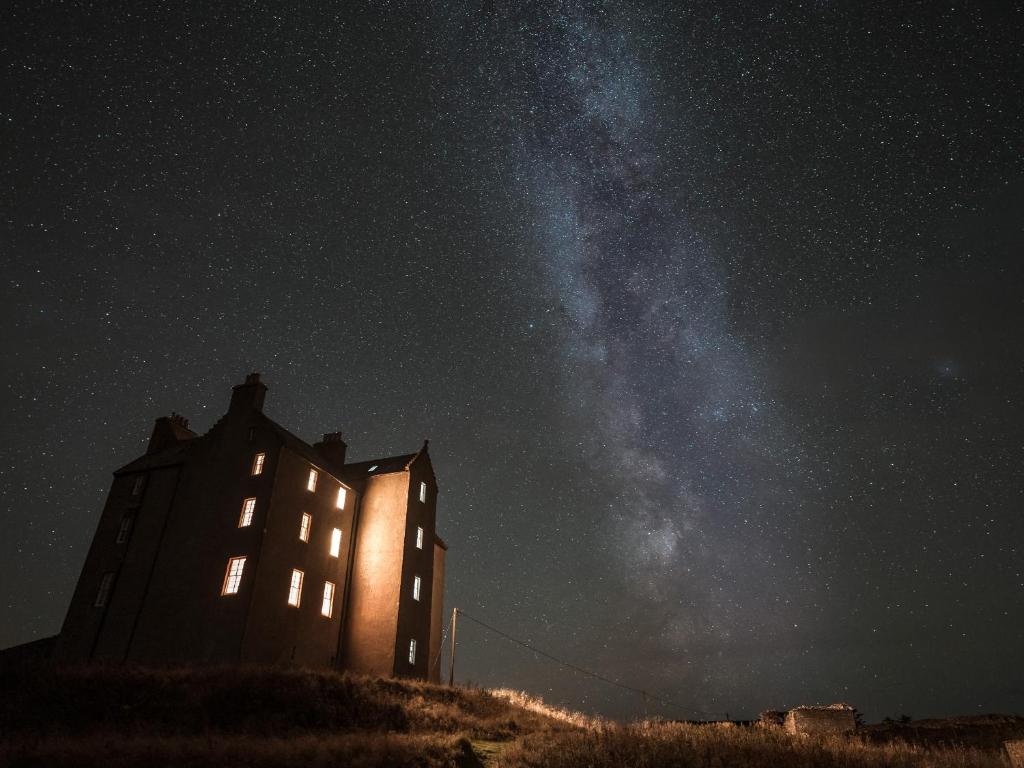 a building on a hill at night with the milky way at Freswick Castle in Wick