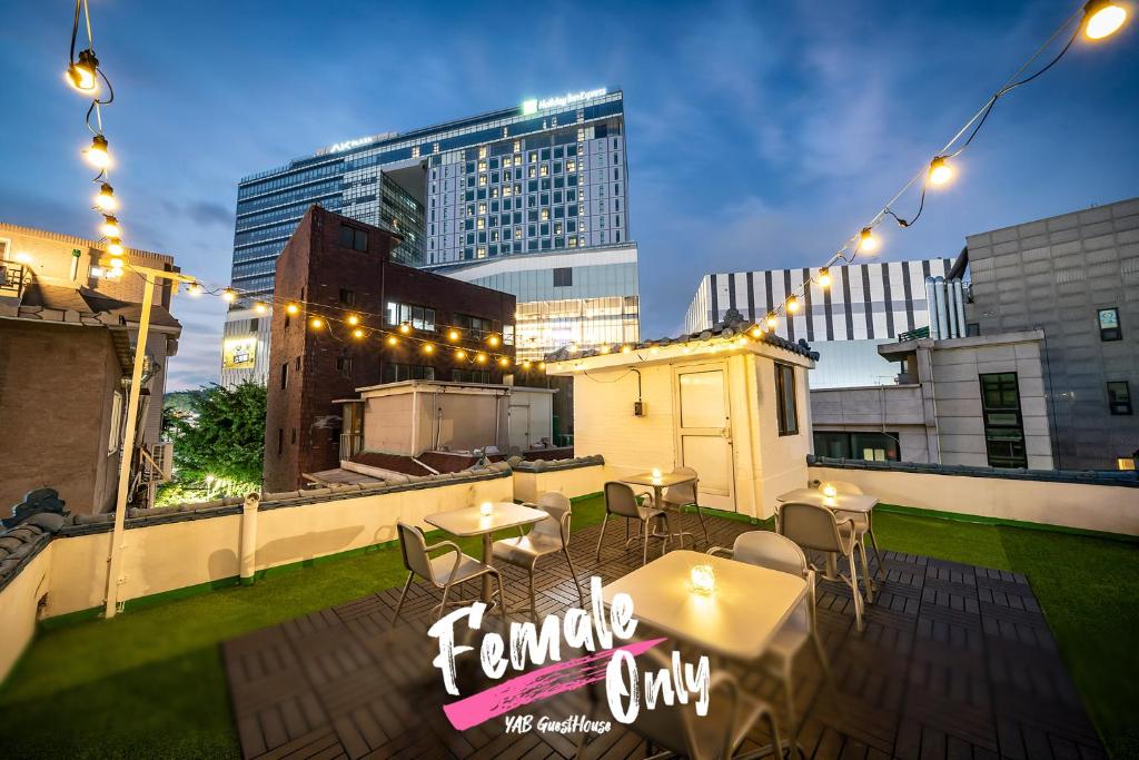 a rooftop patio with tables and chairs and lights at YAB-GuestHouse, FemaleOnly, ForeignOnly in Seoul