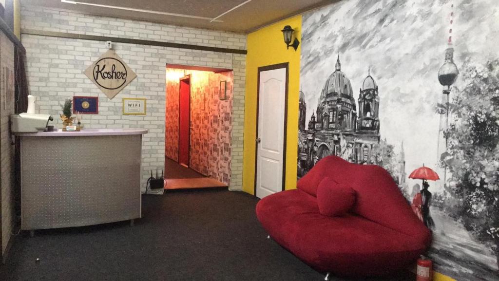 a red chair in a room with a wall with a mural at Kosher Hostel in Odesa