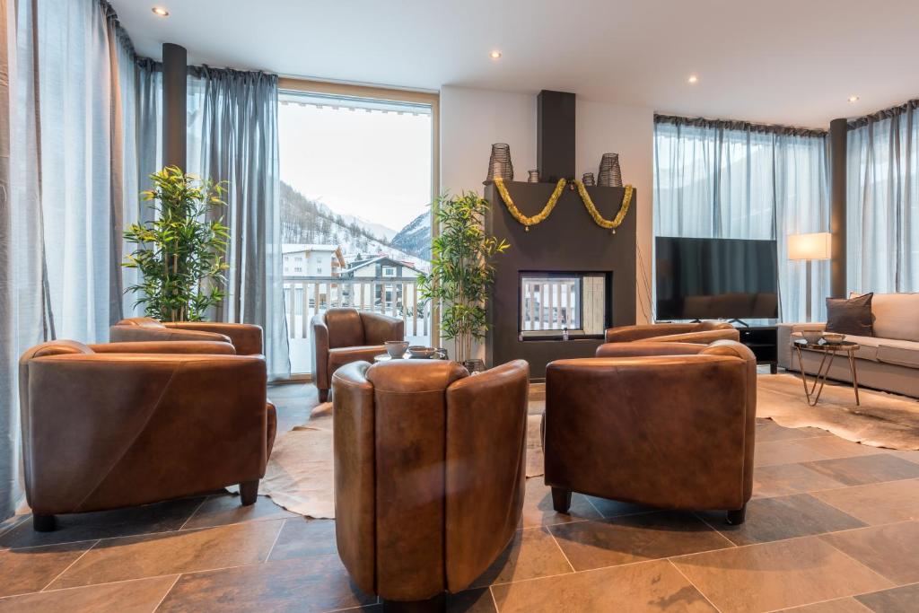 sala de estar con sillas marrones y chimenea en Montela Hotel & Resort - Montela Pavillon, en Saas-Grund