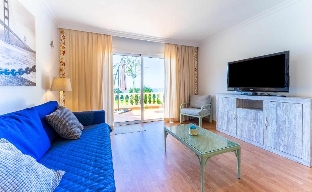 ein Wohnzimmer mit einem blauen Sofa und einem TV in der Unterkunft Apartamento Lázaro 26 Terraza con Vistas al Mar in Santa Úrsula