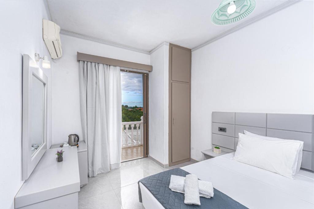 a white bedroom with a bed and a window at Panorama in Laganas