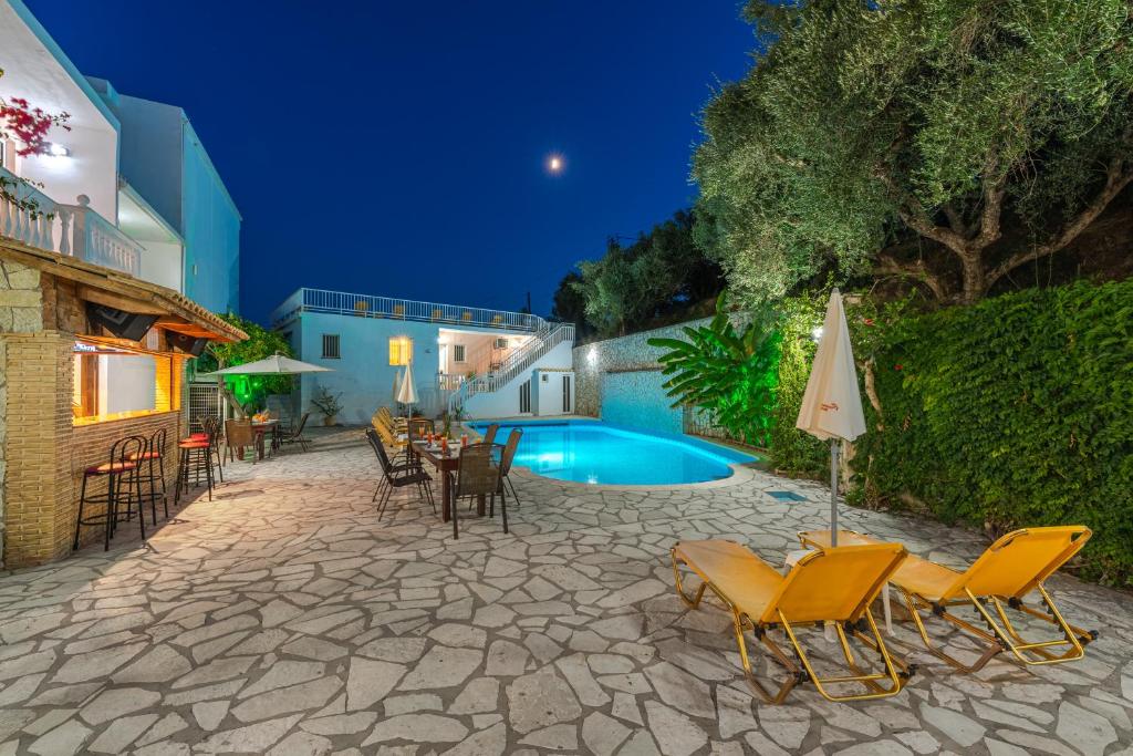 a patio with chairs and a swimming pool at night at Panorama in Laganas