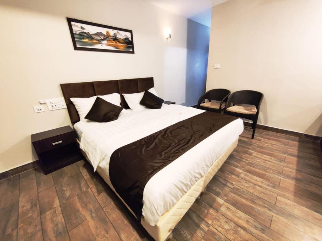 1 Schlafzimmer mit einem großen Bett und 2 Stühlen in der Unterkunft HOTEL PARK KRISHNA in Tirupati
