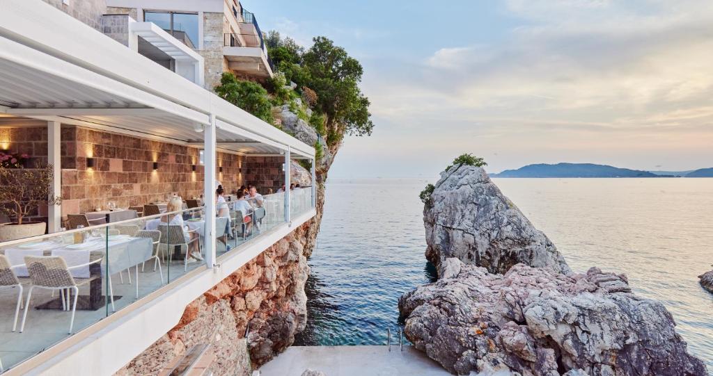 a restaurant on the water next to a cliff at Blanche Cliff Apartments in Sveti Stefan