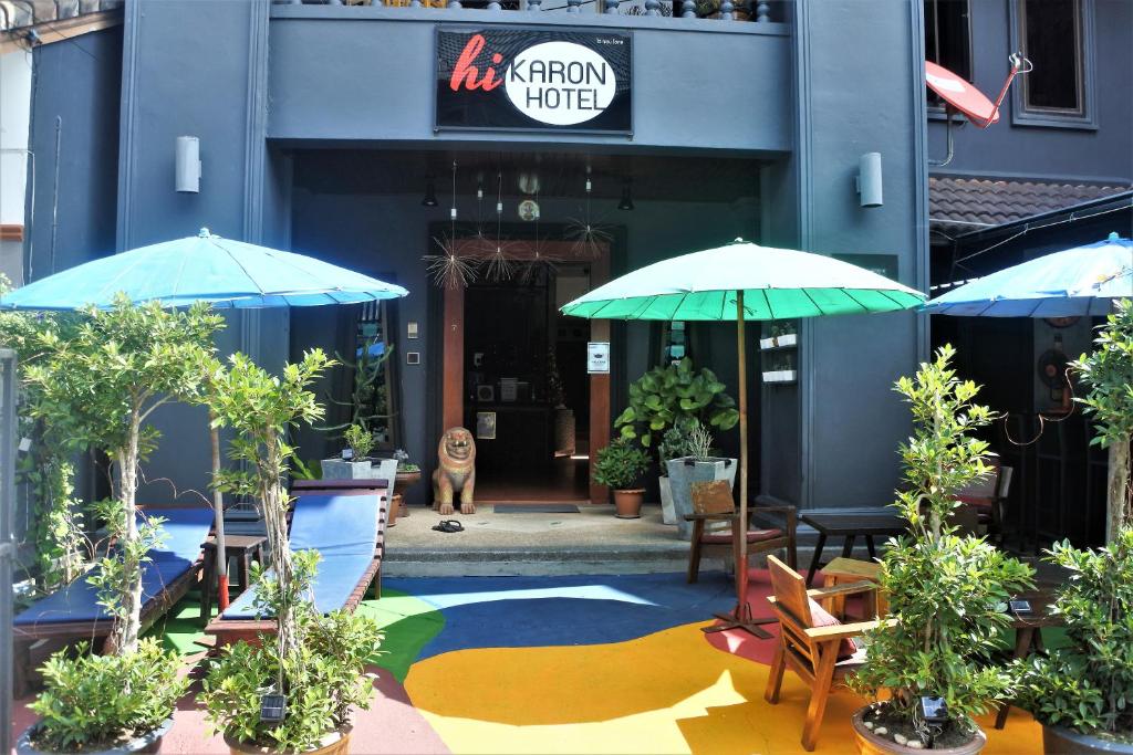 a patio with chairs and umbrellas in front of a building at Hi Karon Beach in Karon Beach