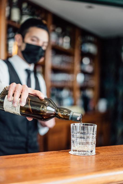 a person wearing a mask pouring a glass at Dormy House in Étretat