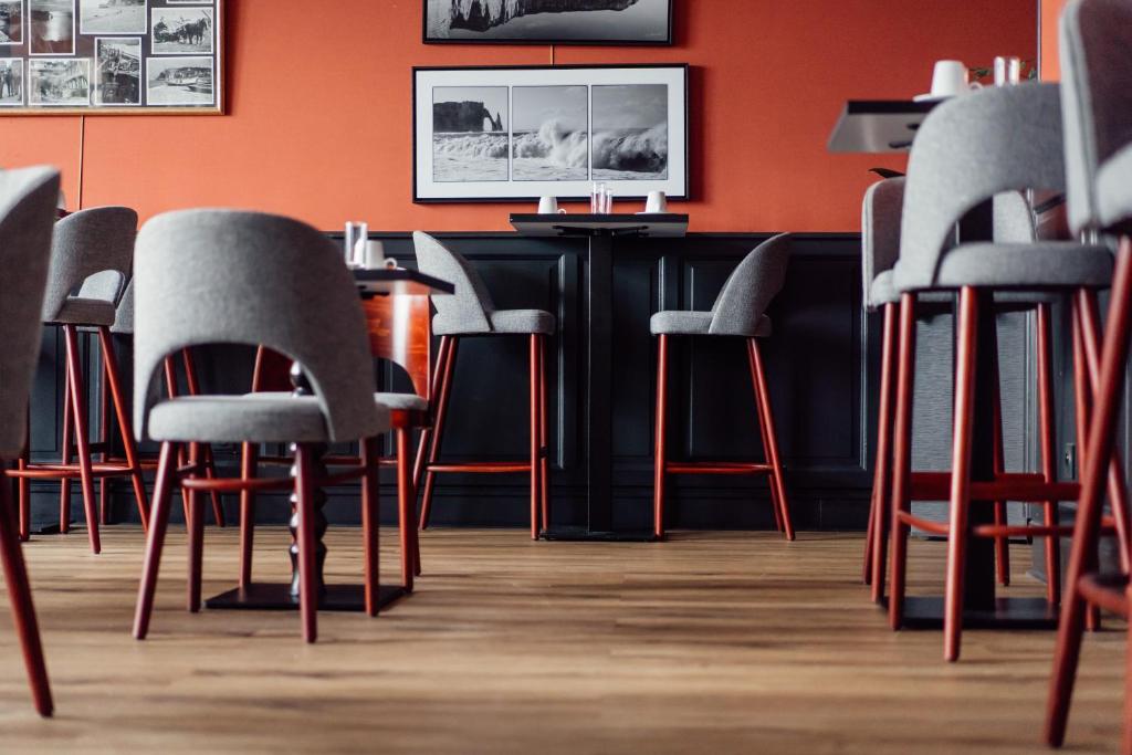 a bar with gray chairs and an orange wall at Dormy House in Étretat