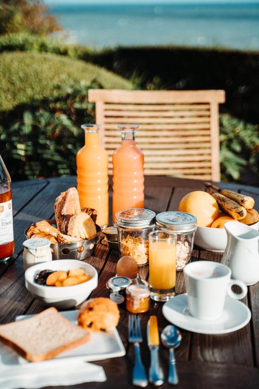 a wooden table with breakfast foods and drinks on it at Dormy House in Étretat