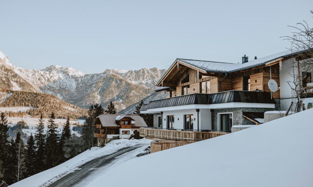 une maison dans la neige avec des montagnes en arrière-plan dans l'établissement Bucheggerhof, à Schladming