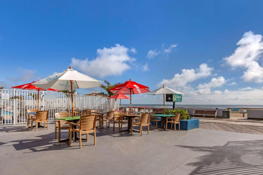 a patio with tables and chairs and umbrellas on the beach at Quality Inn Boardwalk in Ocean City