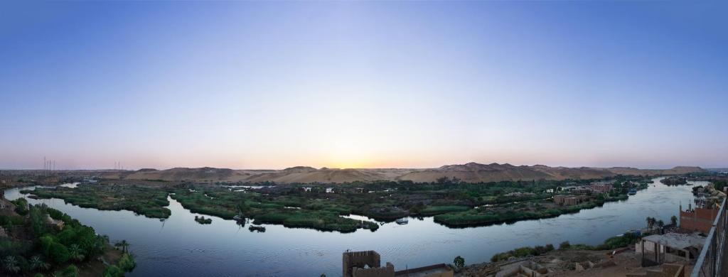 a view of a river with the sun in the distance at ASWAN NILE PALACE (swimming pool-rooftop-Nile view) in Aswan