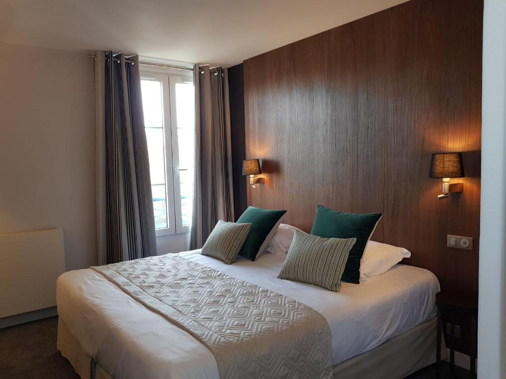 a hotel room with a large bed with green pillows at Dormy House in Étretat