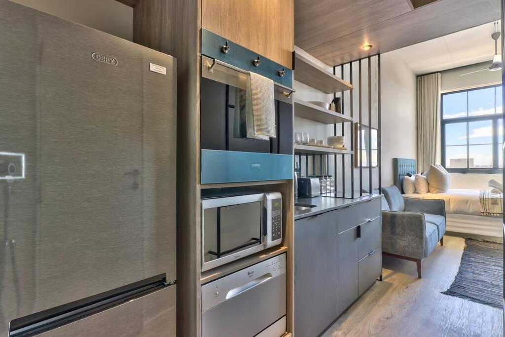 a kitchen with a microwave and a kitchen with a bedroom at Trendy, Urban Living at The Harri w/ Views & WIFI in Cape Town