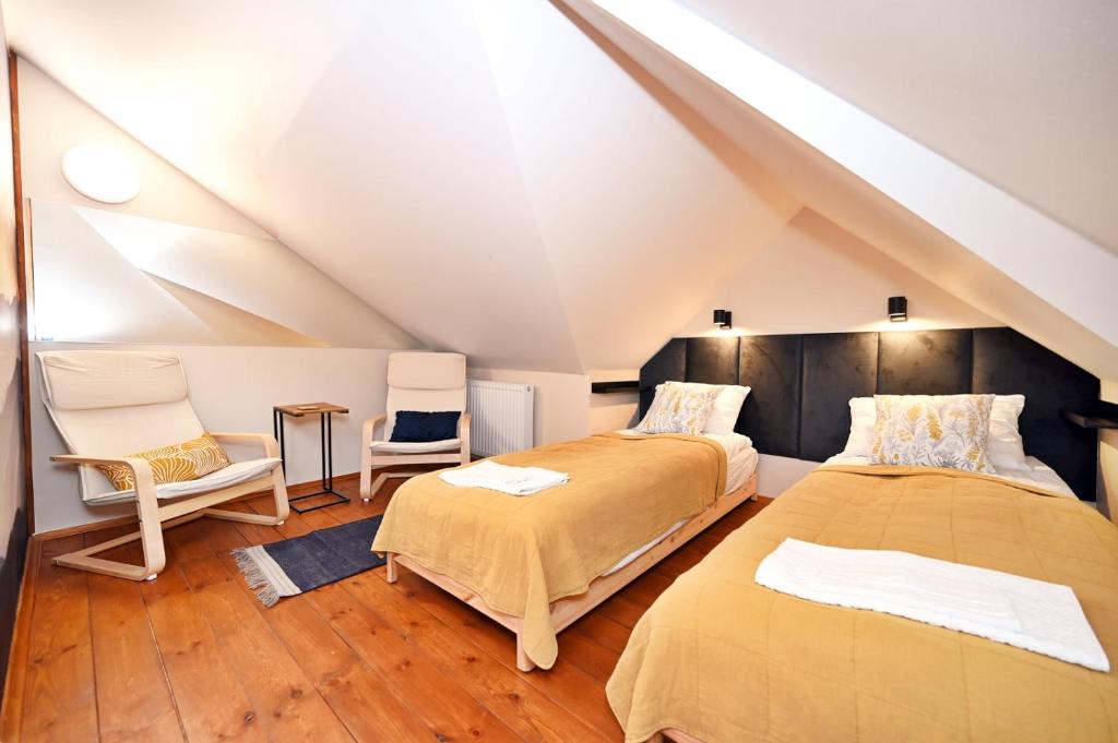 a attic bedroom with two beds and two chairs at Pokoje na Jasnej in Szczyrk