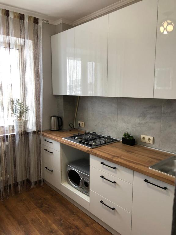 uma cozinha com armários brancos e um forno com placa de fogão em 1кім в Центрі,вул.Набережна em Rivne
