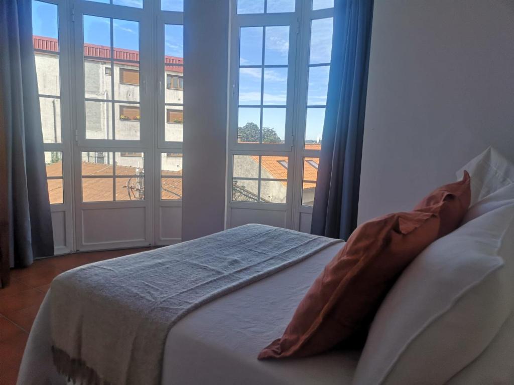 ein Schlafzimmer mit einem Bett und zwei großen Fenstern in der Unterkunft APARTAMENTO AROSA in Vilanova de Arousa