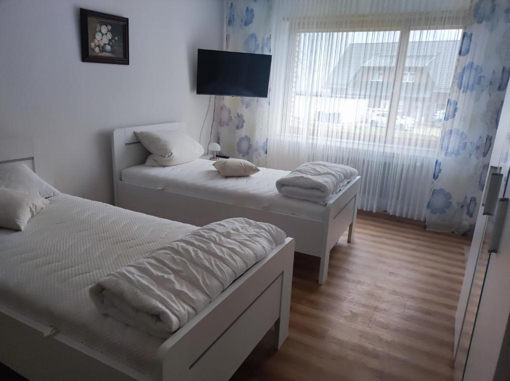 2 Betten in einem kleinen Zimmer mit Fenster in der Unterkunft Wiehenblick in Hüllhorst