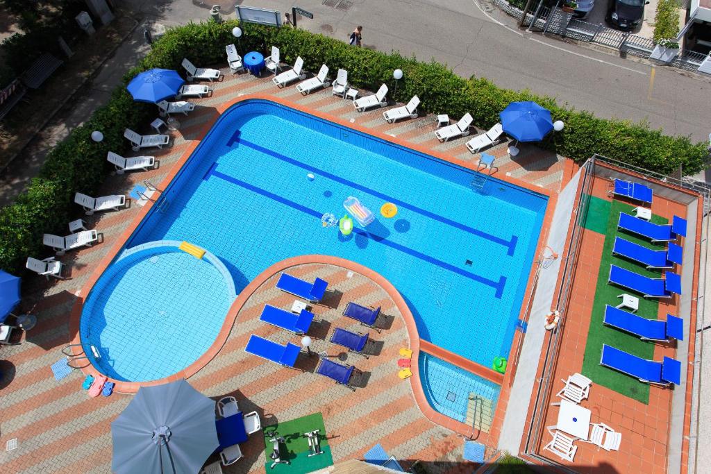 uma vista superior para uma piscina com cadeiras e guarda-sóis em Hotel Real em Cervia