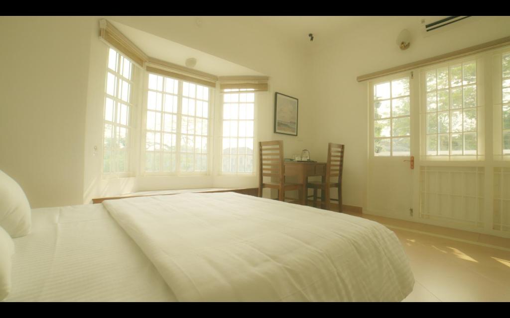 um quarto com uma grande cama branca e janelas em BROOKLANDS AVENUE em Alappuzha