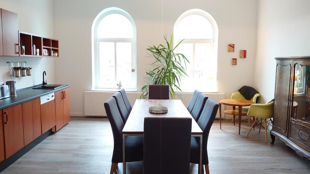 eine Küche mit einem Tisch und Stühlen sowie 2 Fenstern in der Unterkunft Haltestelle - Private Zimmervermietung Röbel Müritz in Röbel