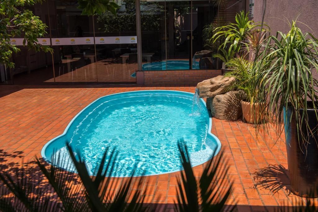 a blue swimming pool in a courtyard with plants at Pousada Nanai in Foz do Iguaçu