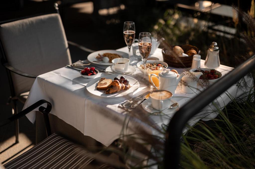 un tavolo bianco con cibo e bicchieri di vino di Hotel Pollinger a Merano