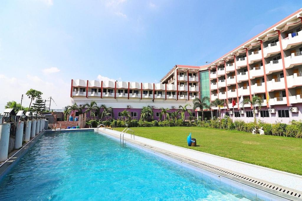 un hôtel avec une piscine en face d'un bâtiment dans l'établissement MADHU MAMATA HOTEL, à Tarapith