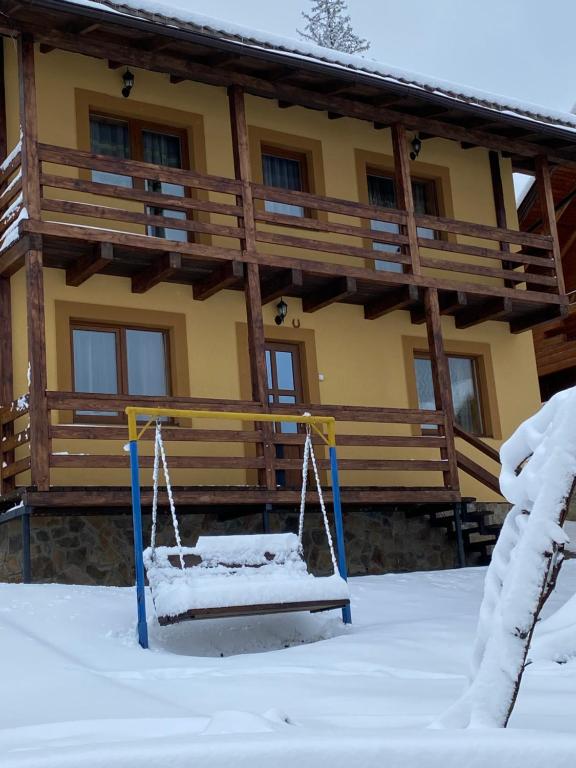 スラブスクにあるТри богатиріの雪の中のブランコ付きログキャビン