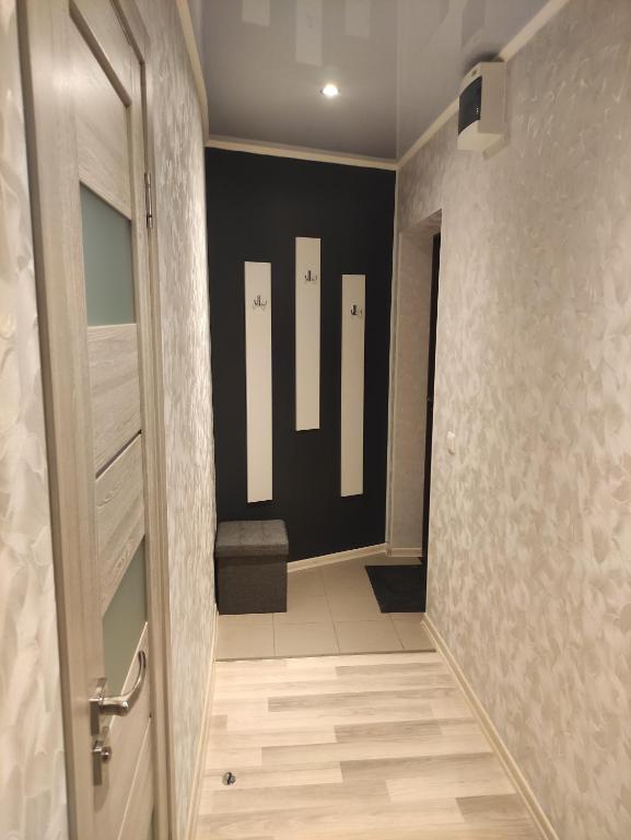 un pasillo con una puerta que conduce a un baño con banco en VA Apartments, en Rēzekne