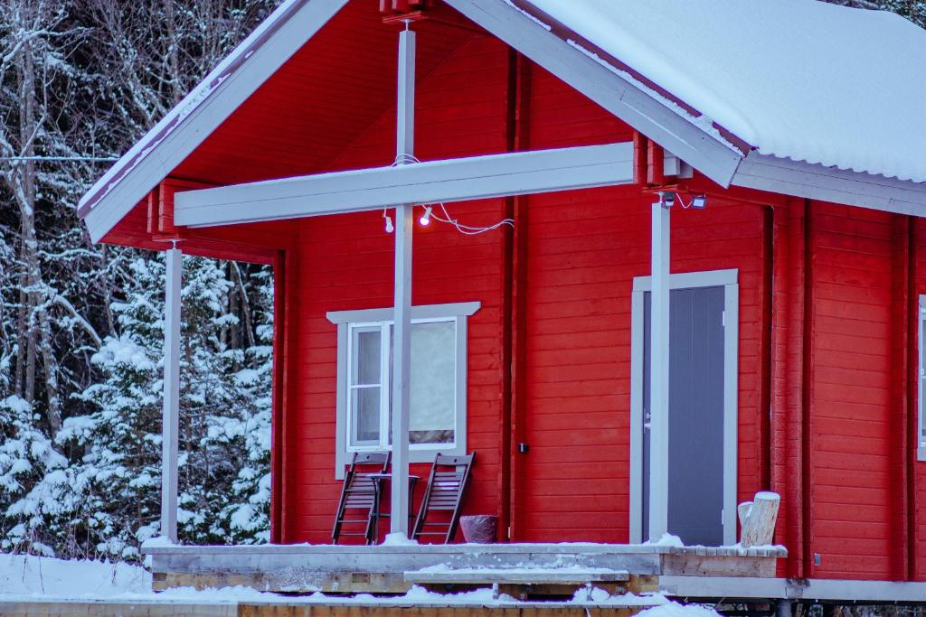 a red house with two chairs outside in the snow at Дом LBerry Брусника у Ладоги in Sortavala