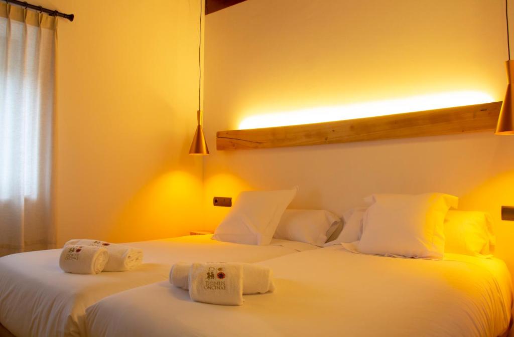 two beds in a hotel room with white sheets at Domus Oncinae in Oncina de la Valdoncina