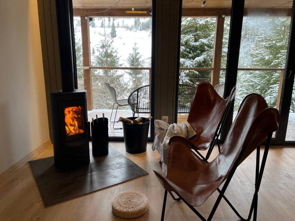 a living room with a fireplace and two leather chairs at Над фермою in Nizhne-Studënyy