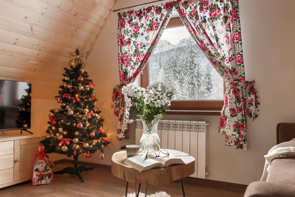 a living room with a christmas tree and a window at Apartamenty VILLA SKI-BÓWKI in Zakopane