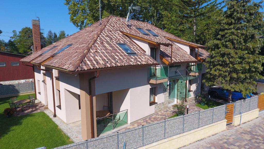 una casa con techo de baldosa y valla en Fenyves Apartmanok, en Balatonfenyves