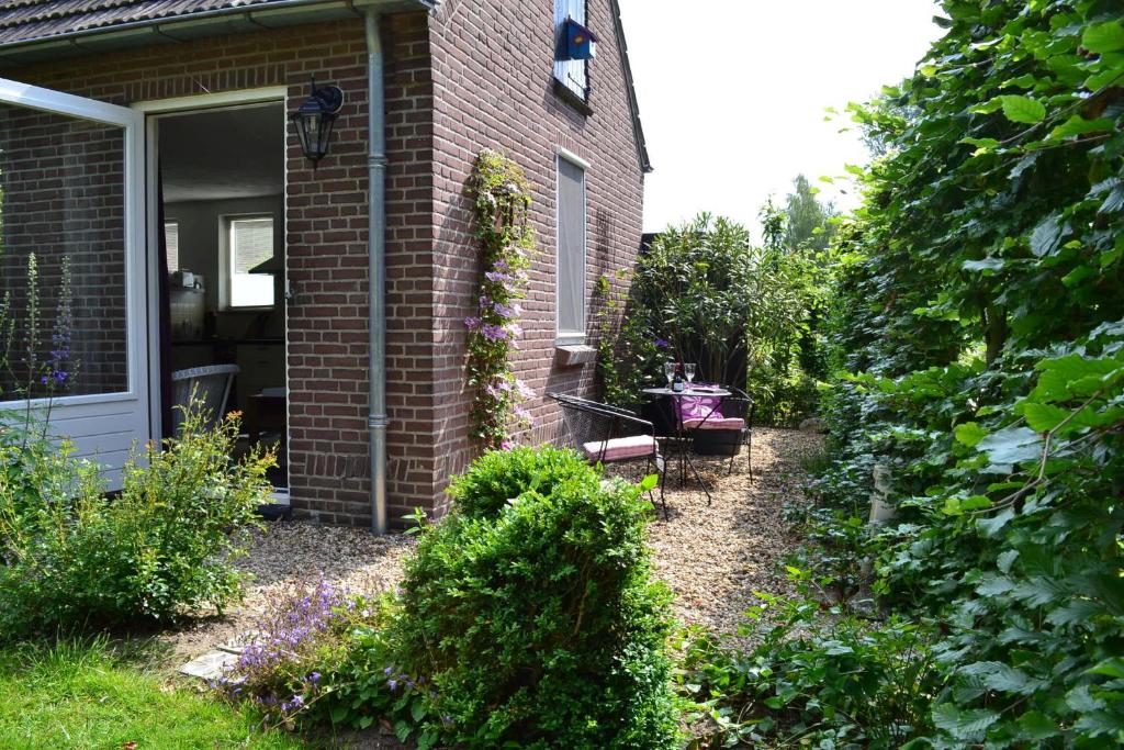 einen Garten außerhalb eines Hauses mit einem Fenster in der Unterkunft Appartement De Bosuil in Groesbeek