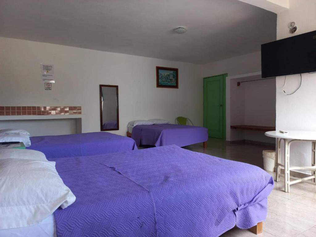 - 2 lits dans une chambre avec des draps violets dans l'établissement Airport Sleepy Inn, à Cancún