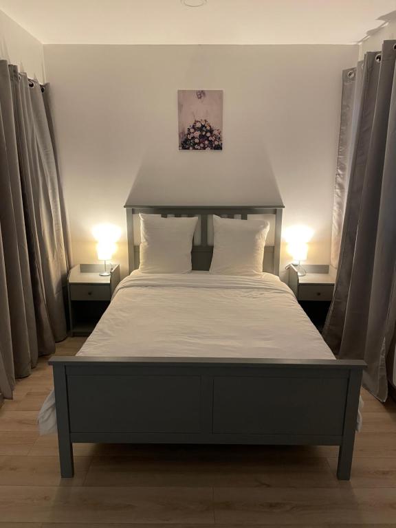 um quarto com uma cama grande com lençóis brancos e almofadas em Résidence Chene em Viry-Châtillon